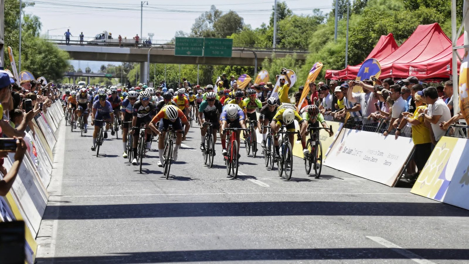 Ciclistas cruzando el arco de llegada acompañados por el público